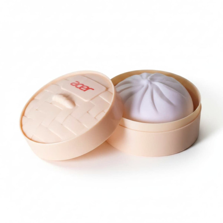 A squishy bun in a round, light peach container with a lid, featuring a soft purple bun inside.