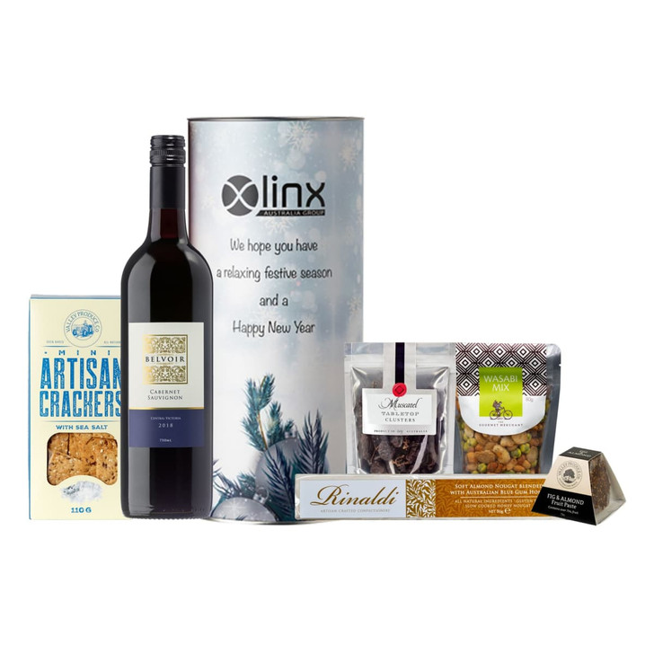 A Cabernet wine bottle, artisan crackers, nuts, and chocolate in a festive hamper packaging with branding.