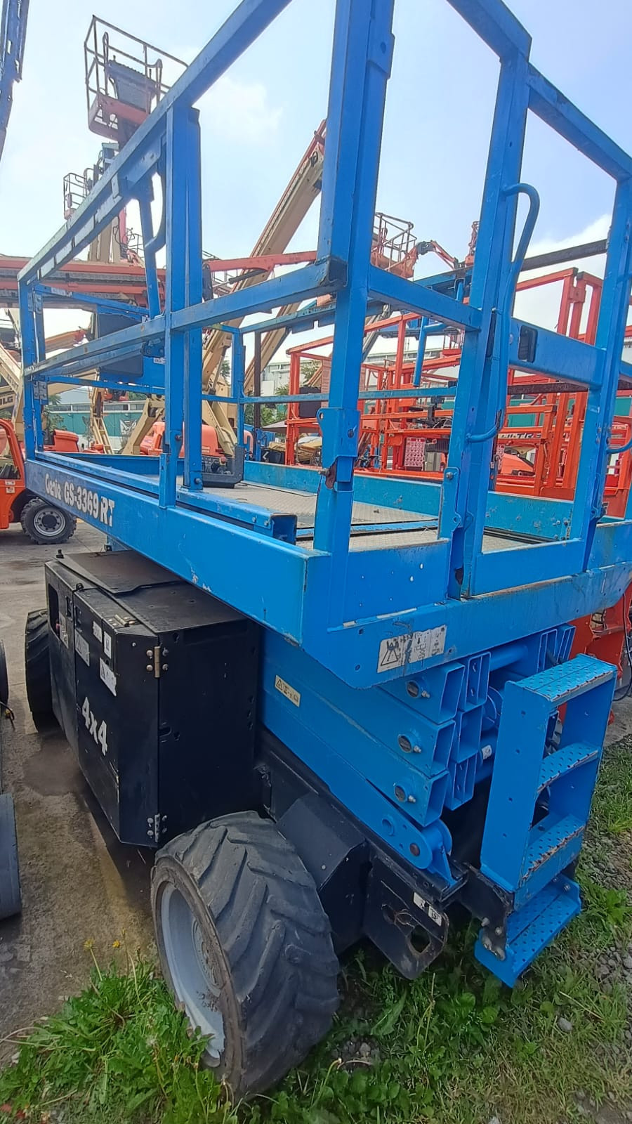Plataforma de tijera móvil industrial de color azul estacionada en zona de maniobras