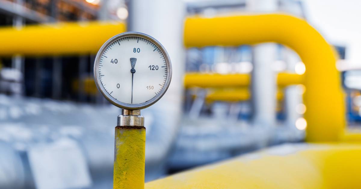 A pressure gauge connects to a large yellow pipe. It has small markings, including the numbers 20, 40, 80, 120, and 150.