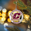 Central Michigan Chippewas ornament, maroon and gold logo on silver background, hanging on evergreen tree branch with blurred lights.