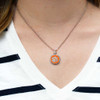 Clemson Tigers cutout necklace, orange and silver pendant with paw print design on a chain, displayed on a person wearing a white and black striped shirt.