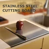 Stainless steel cutting board with a knife and red apple on a kitchen counter, ideal for chefs and home cooks.