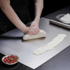 Stainless steel cutting board with dough on it, for chefs and home cooks, kitchen utensil, large silver board for food preparation.