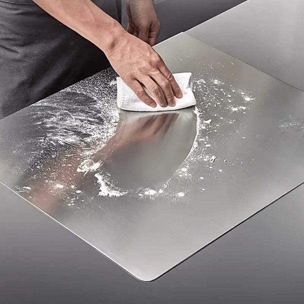 Stainless steel cutting board with lip, being wiped clean with a cloth, for kitchen use, made of durable stainless steel material easily.