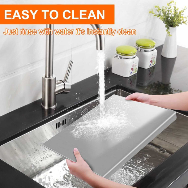 Stainless steel cutting board with lip, being rinsed under running water in a kitchen sink, Honesty House brand, silver color.