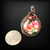 Copper wire wrapped pendant with a glass cabochon depicting pink roses and accented with a red glass bead