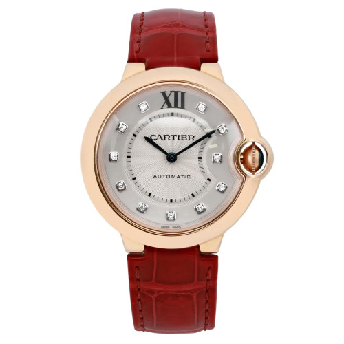 An image of a pre-owned Cartier Ballon Blue women's 36mm 18k rose gold diamond silver dial wristwatch, positioned upright and facing forward. The watch features a round face with a rose gold case and diamond hour markers. The dial is silver with Roman numeral XII at the top and the brand name "Cartier" in the center. It has a red leather strap with visible stitching. The photo is taken from a close, eye-level angle, capturing the watch in clear detail.