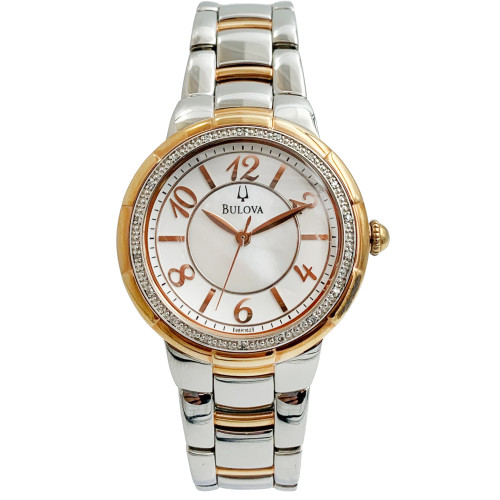 An image of a pre-owned Bulova wristwatch for women, displayed frontally with a direct view of the watch face. The watch is positioned vertically with the 12 o'clock mark at the top, approximately at eye level. The wristwatch features a round, rose gold-tone bezel adorned with diamonds, a white dial with rose gold-tone hands, and Roman numeral hour markers. The Bulova logo is visible below the 12 o'clock mark. The bracelet is silver and rose gold-tone with a center folding clasp, visible in full from the watch face down. The image is shot from a close distance, showing clear details of the watch's design and condition.