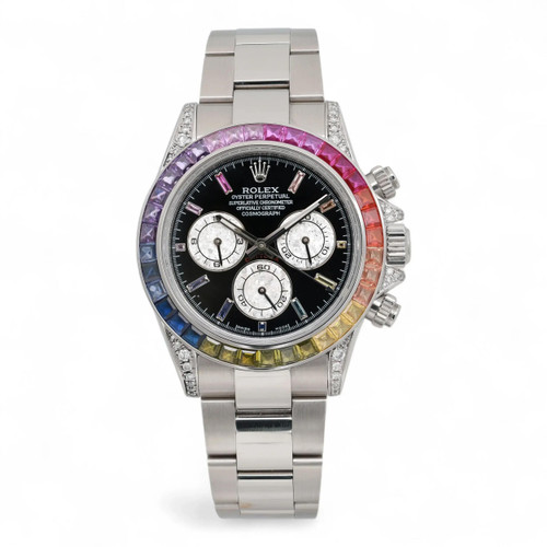 An image of a pre-owned men's Rolex Cosmograph Daytona 40mm Custom Rainbow Bezel Black Dial Watch 116520 is shown from a front angle, highlighting its vibrant, multicolored bezel. The watch face is black with three subdials for chronograph functions, accompanied by luminous hands and a small seconds subdial. The stainless steel bracelet is visible, and the image is taken from a close distance, capturing the intricate details of the watch's design.