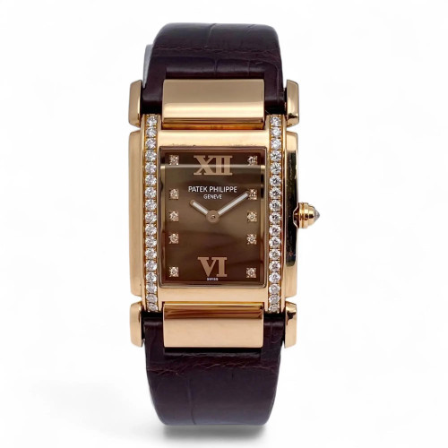 An image of a pre-owned women's Patek Philippe twenty-4 18K Rose Gold Diamond Chocolate Dial Ladies Watch 4920R wristwatch captured from a front-facing angle. The watch features a rectangular face with a chocolate dial, Roman numerals at the 12 and 6 positions, and diamond hour markers. The case is bordered with a double row of sparkling diamonds, and the watch is fitted with a dark leather strap. The image is taken at a close distance, highlighting the luxurious details and craftsmanship.