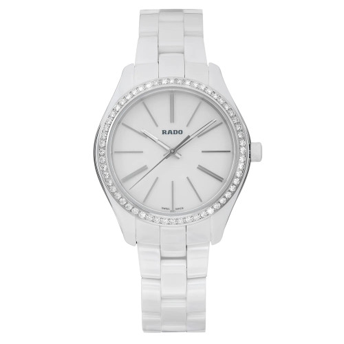 An image of an unworn Rado wristwatch for women in a casual style, presented in a full frontal view. The watch features a round white dial with non-numeric hour marks and stick indexes, as well as a seconds hand and luminous hands. It has a gray diamond bezel and the band is made of white ceramic with a steel/cemaric case. The watch is positioned centrally with the band partially extended, creating a slight curve at the bottom, against a neutral background. Distance from the view is close enough to clearly show the details of the watch face and band. The condition is excellent, indicating the watch is unworn.