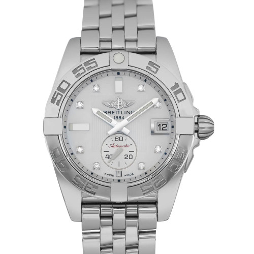 An image of a pre-owned Breitling unisex adult wristwatch presented in a full frontal view. This luxury timepiece features a round shape with a white mother of pearl dial, diamond markers at the hours, and a gray bezel. The watch has a stainless steel band and case, and is shown from a straight-on angle with a clear view of the dial that includes a date indicator and a small seconds subdial. The hands are luminous, and the watch is in good condition. The Breitling logo and the year 1884 are visible on the dial, indicating the brand's heritage. The photo is taken from a close distance, allowing for detailed inspection of the watch's features.