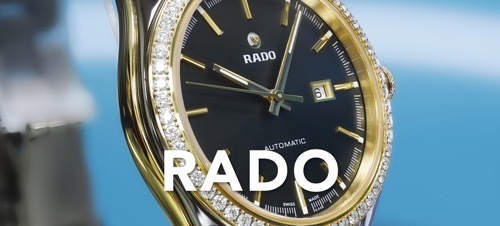 IMAGE OF A CERAMIC RADO WATCH WITH BLACK DIAL AND DIAMONDS ON BLUE BACKDROP