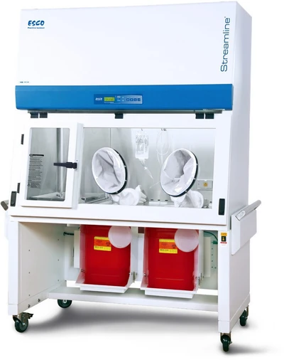 Esco Streamline SLC-RABS compounding aseptic containment isolator, 4 ft, two oval gloveports, with sharps disposal containers on the motorized stand Cabinet pictured is a positive-pressure unit; the cabinet is identical across pressure schemes.