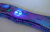 UV-reactive Heretic Knives logo glowing on Shipwreck Cel Shade handle under ultraviolet light