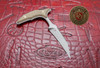 Microtech Marfione Select Bastinelli Bee fixed blade push dagger with apocalyptic blade and titanium handle displayed on red Microtech leather mat.