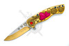 Close-up of gold assisted opening knife with heart cutout blade and ruby red jewel accent