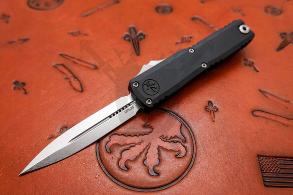 Front angled view of Microtech UTX-70 automatic knife with dagger blade and black aluminum handle