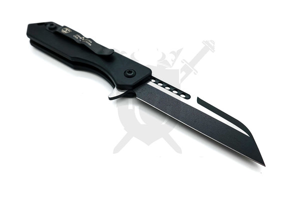 Heretic Jinn manual button lock knife open showing two-tone black MagnaCut sheepsfoot blade and black aluminum handle with pocket clip