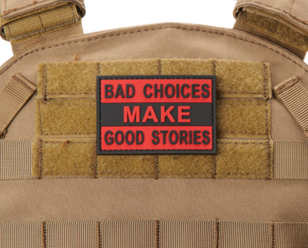Red and black PVC morale patch reading “Bad Choices Make Good Stories” mounted on a tactical vest with hook-and-loop backing.