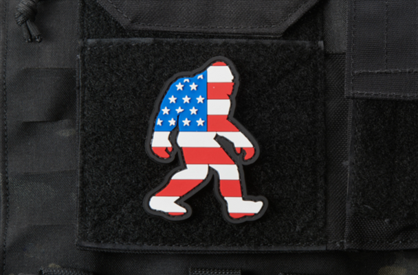 PVC morale patch featuring a Bigfoot silhouette filled with a USA flag design, mounted on a tactical vest with hook-and-loop backing.