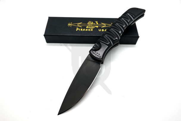 Piranha Paradox automatic knife with black 154CM drop point blade and CNC-machined black aluminum handle, shown open at an angle with pocket clip visible.