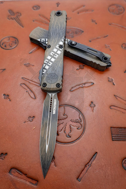 Microtech Ultratech Gen IV Wookiee OTF automatic knife with double edge dagger blade opened on Microtech leather display mat