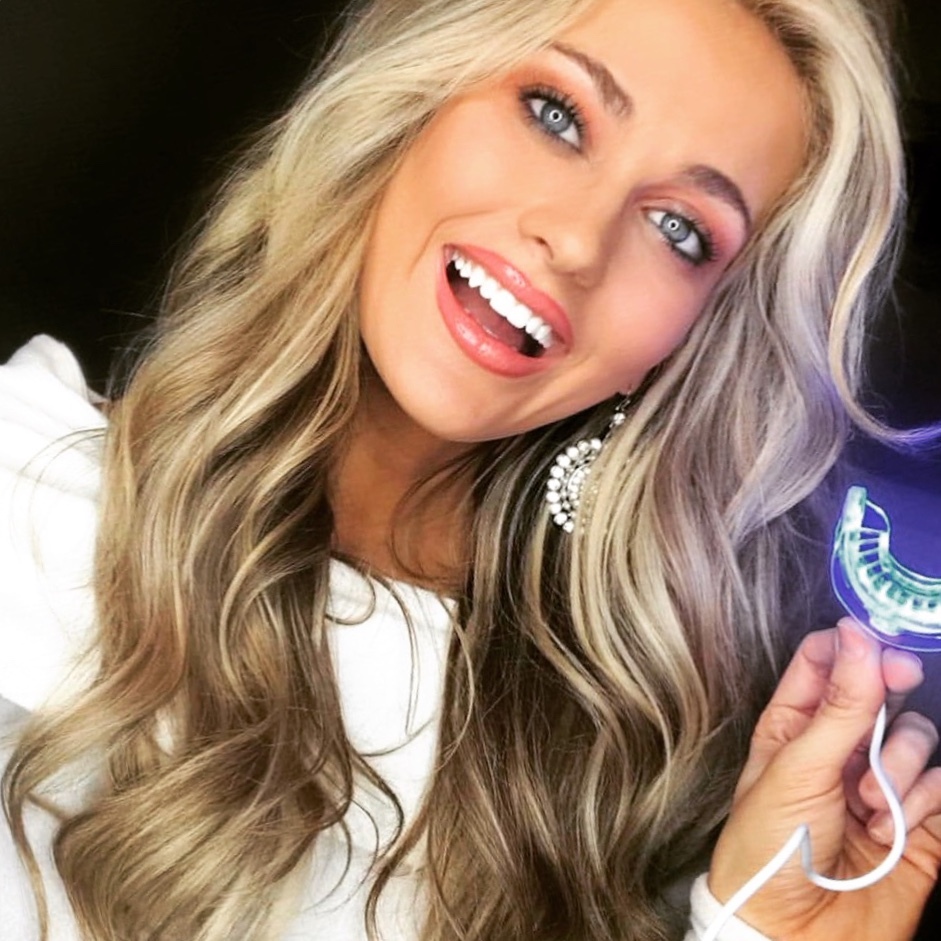 customer whitening her teeth with the ibright smartphone whitening system