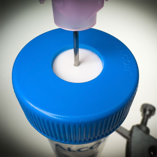 50 ml Type-F blue centrifuge cap with an uncut SeptaSecure septum being punctured by a needle demonstrates the lid's strong yet penetrable silicone membrane designed for controlled access. This setup is ideal for controlling contamination in laboratory procedures.