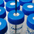 A close-up view of multiple 50 mL Falcon tubes capped with blue SeptaSecure lids, each featuring a white cross-cut septum. A needle is inserted into one of the caps, demonstrating the centrifuge tube cap's easy-access functionality in a laboratory setting.