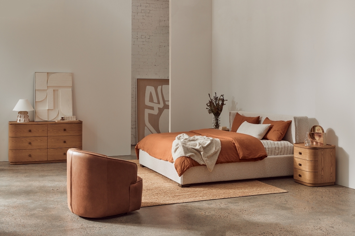 A bedroom setting in warm tones, styled with bedlinen and hard furnishings
