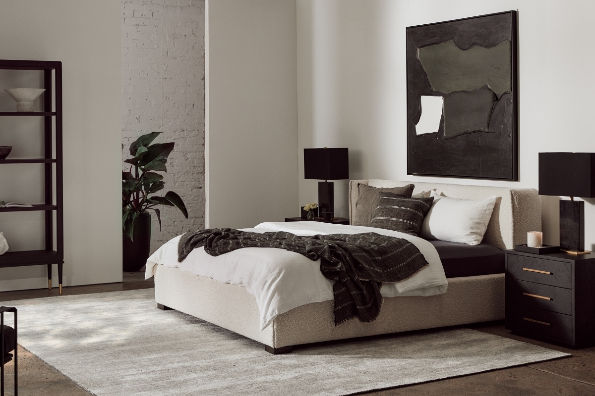 A bedroom setting in cool tones, styled with bedlinen and cushions