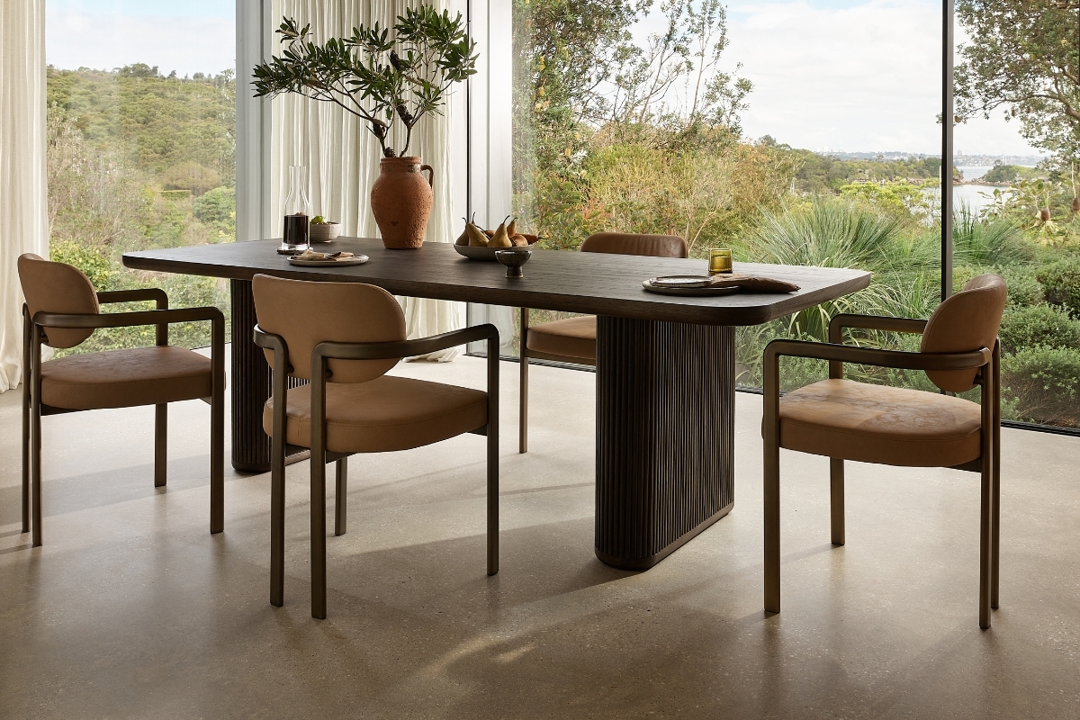 Contemporary dining room featuring Stuttgart Dining Chairs in tan vegan leather with curved arms, styled around a dark timber pedestal table.