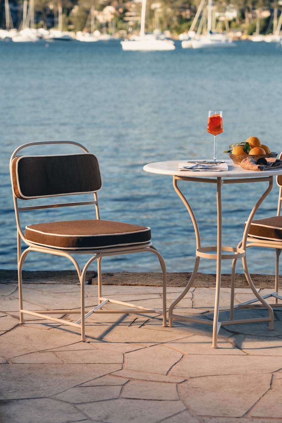 Outdoor bistro chair and marble-top table on a sandstone terrace by the water
