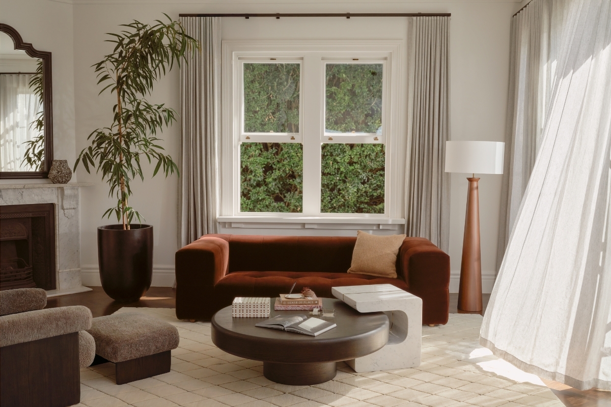 Earth-toned living room with rust velvet sofa, sculptural coffee table and layered neutral rug