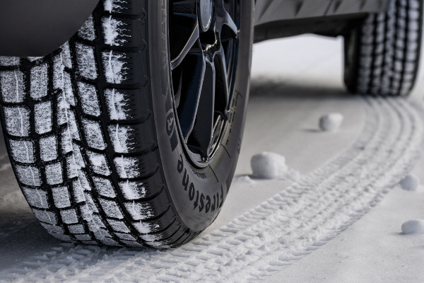 Close photo of a winter tire in snow on a vehicle