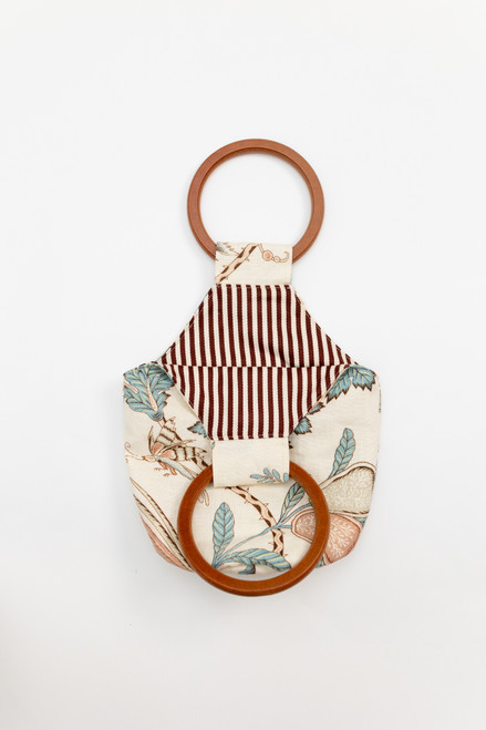 Beige purse/bag that has a light orange and blue leafy/floral design and a brown striped interior. Comfortable wooden handle that is reliable and chic. Great for gifts, dinner, travel, vacation, and everyday wear! Beige purse/bag that has a light orange and blue leafy/floral design and a brown striped interior. Comfortable wooden handle that is reliable and chic. Great for gifts, dinner, travel, vacation, and everyday wear!