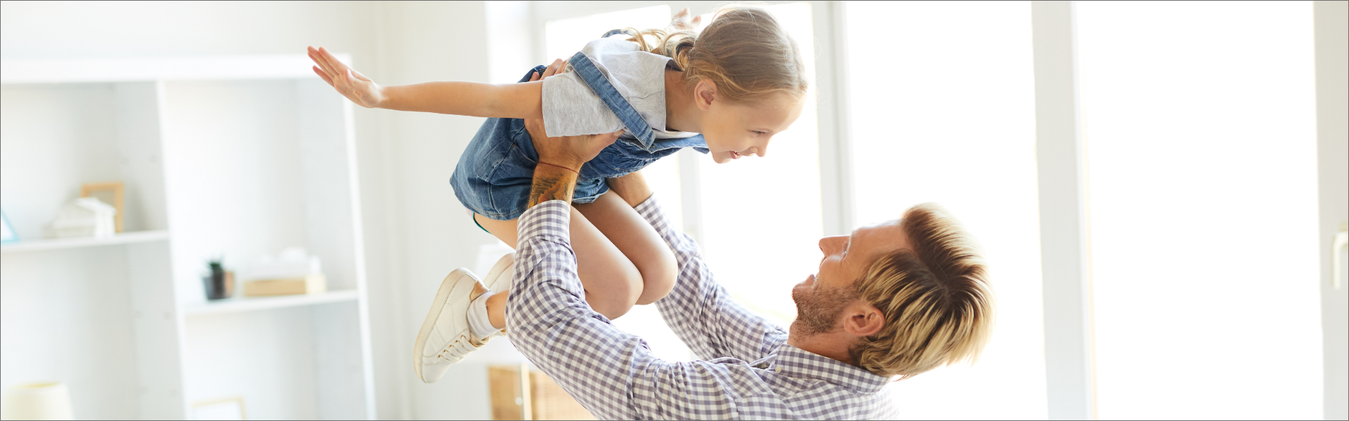 father holding a little girl over his head while playing with her