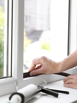 person applying foam weatherstripping to a window