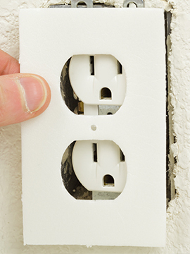 person installing outlet foam gasket to outlets