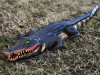4 foot swamp alligator Halloween decoration with green eyes, sharp teeth, and long tail on grass