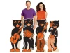 Two people stand behind four retro-style black cat cardboard cutouts with orange accents, each cat playing a different instrument.