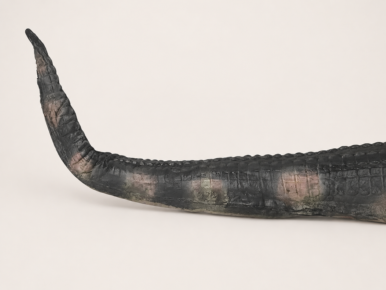 Close-up of alligator crocodile Halloween prop tail showing dark textured finish and painted detail