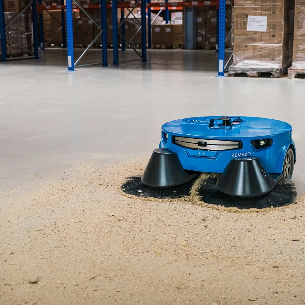 KEMARO K900 autonomous sweeper collecting wood dust and dry debris from a warehouse floor