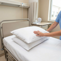 white-130-thread-count-wholesale-polycotton-institutional-pillowcases-on-hospital-bed-hand-demonstrating-durable-polycotton-fabric-housewife-style-institutional-setting-lifestyle