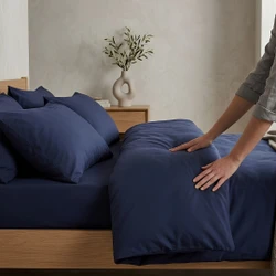navy-blue-100-percent-polyester-microfibre-bedding-on-bed-hand-demonstrating-soft-wrinkle-resistant-fabric-bedroom-lifestyle