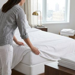 white-180-thread-count-percale-flat-sheets-lifestyle-hands-folding-bedding-on-wooden-table