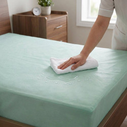 green-tint-waterproof-flame-retardant-mattress-protector-on-mattress-hand-demonstrating-water-resistant-properties-water-beading-off-surface