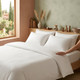 white-200-thread-count-easy-iron-cotton-rich-satin-stripe-duvet-cover-on-bed-hand-demonstrating-soft-fabric-sateen-stripe-design-bedroom-lifestyle